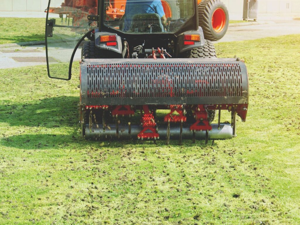 Lawn aerator machine loosening compacted grass soil.