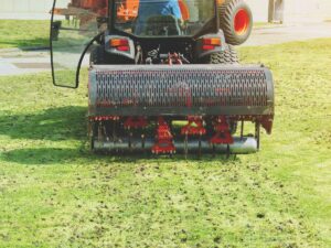 Lawn aerator machine loosening compacted grass soil.